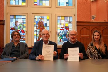 Der Landrat und der Vorsitzende des Sozialdienstes halten die Kooperationsvereinbarung in den Händen, neben ihnen sitzen der Sozialdezernent und eine Mitarbeiterin des Sozialamtes