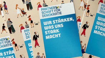 Mehrere gleichaussehende Flyer der Partnerschaft für Demokratie Landkreis Sankt Wendel.