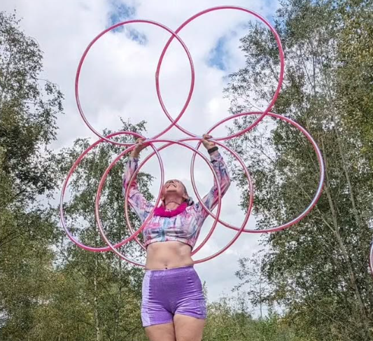 Hula-Hoop-Künstlerin balanciert fünf Hula-Hoop-Reifen in der Luft