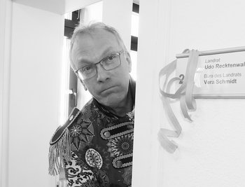 Landrat Udo Recktenwald steht an einer Tür und blickt traurig